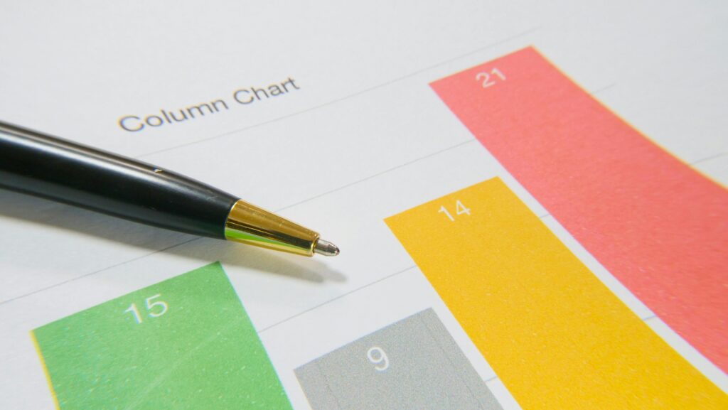 Close-up image of a colorful column chart and pen symbolizing financial analysis.