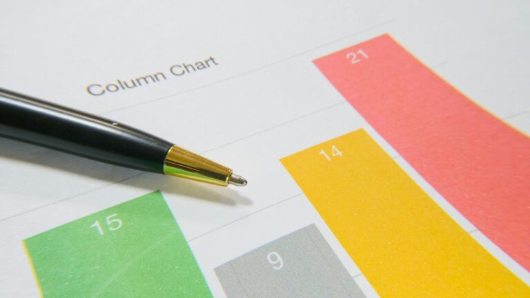 Close-up image of a colorful column chart and pen symbolizing financial analysis.